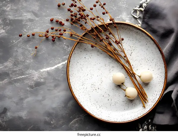White Plate with Dried Flowers and White Berries on a Grey Background