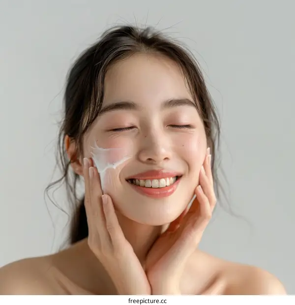 Asian woman applying moisturizer to her face