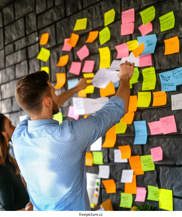 Man Putting Sticky Notes on Wall for Brainstorming