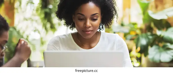 African American Woman Working on Laptop in a Green Cafe