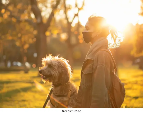 A masked woman walking her dog in the park