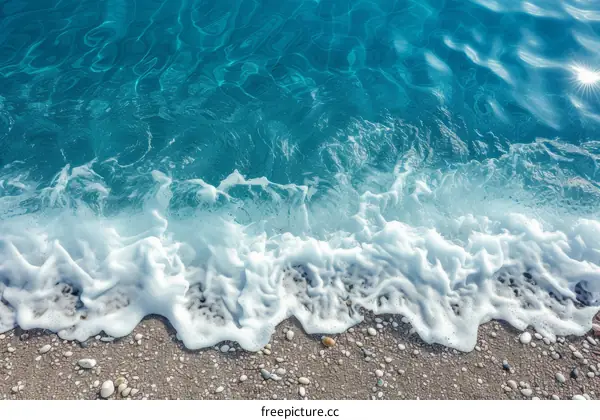 Azure sea water with white foam and pebble beach