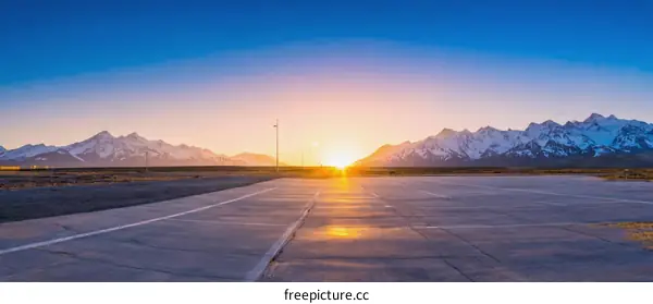 Sunrise over Snowy Mountains and Empty Runway