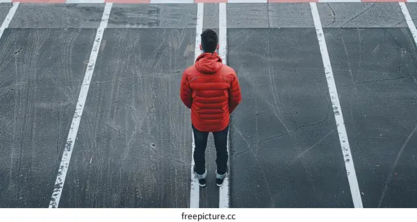 man in red jacket standing alone on the road