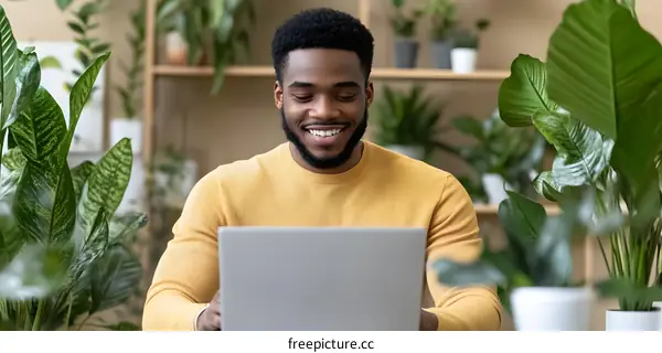 Smiling Black Man Using Laptop in a Green Office Space