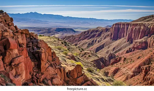 A majestic canyon landscape with red rocks and mountains in the background