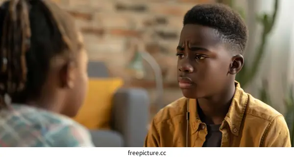 A serious young African-American boy looking at another person