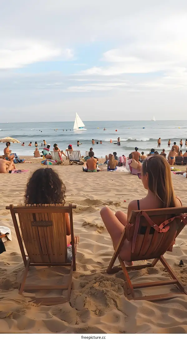 Two Women Relaxing on Beach Chairs Facing the Ocean with Sailboat in the Distance