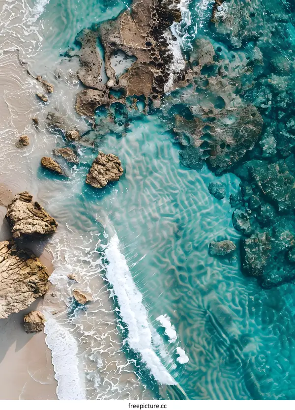Aerial View of Turquoise Water Crashing on Sandy Beach with Rocks