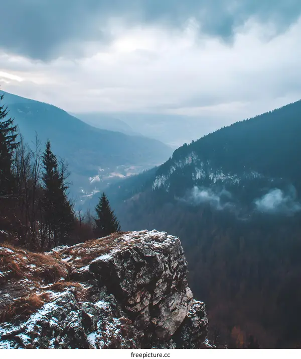 Mountain Cliff Overlooking Forested Valley With Fog