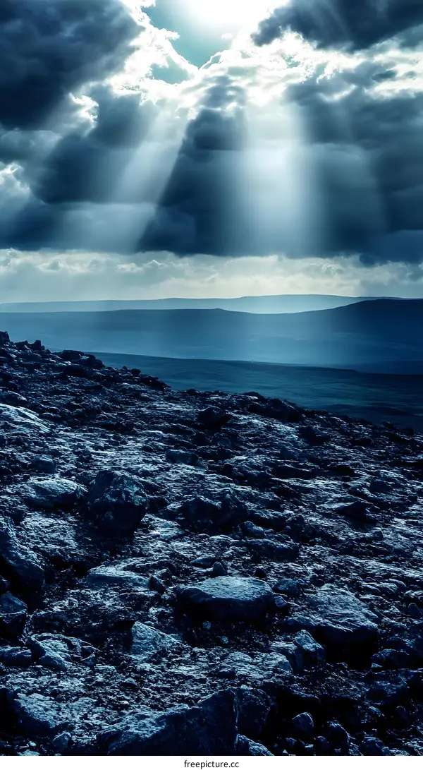 Rays of Sunlight Breaking Through Dark Clouds Above Rocky Landscape