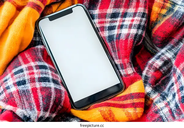 Smartphone with Blank Screen Lying on Plaid Blanket
