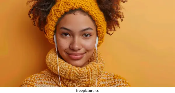 Smiling young woman wearing a yellow sweater and headphones