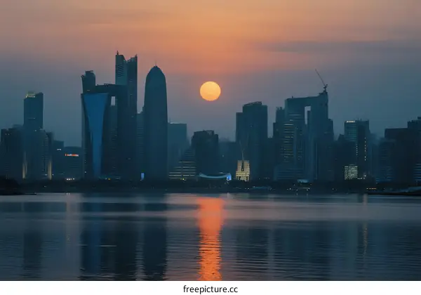 Sunset Over Modern Cityscape with Reflective Water Surface