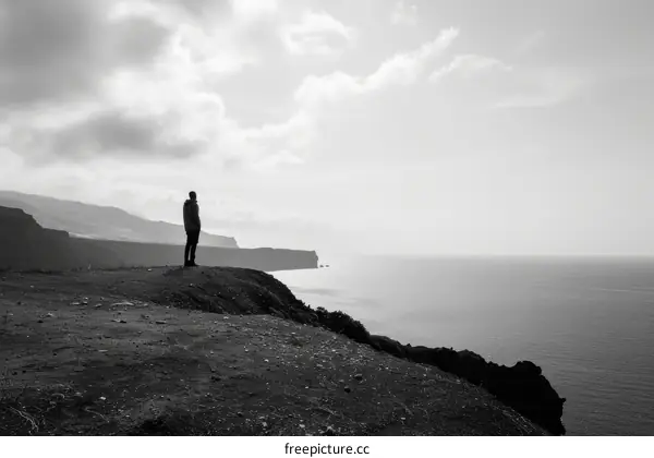 Man standing alone on a cliff overlooking the ocean