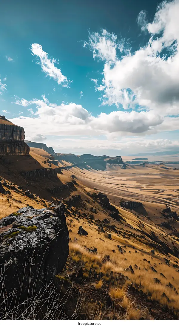 Stunning View Of A Mountain Range With Grass And Rocks Under A Blue Sky With Clouds
