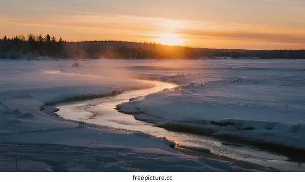 Sunset over a frozen river with mist rising in winter