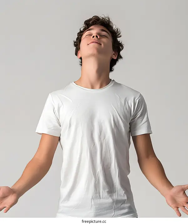 Young man in white shirt with eyes closed and arms outstretched