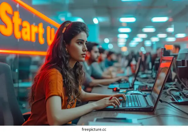 A young woman working on a laptop in a brightly lit office.