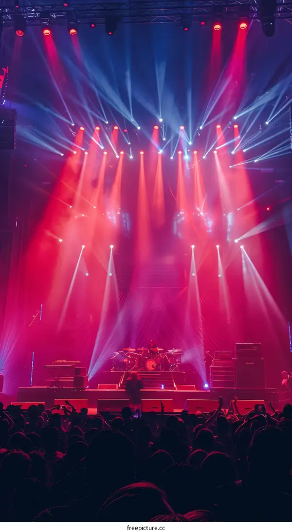 Red and blue stage lights at a concert with a crowd in the foreground