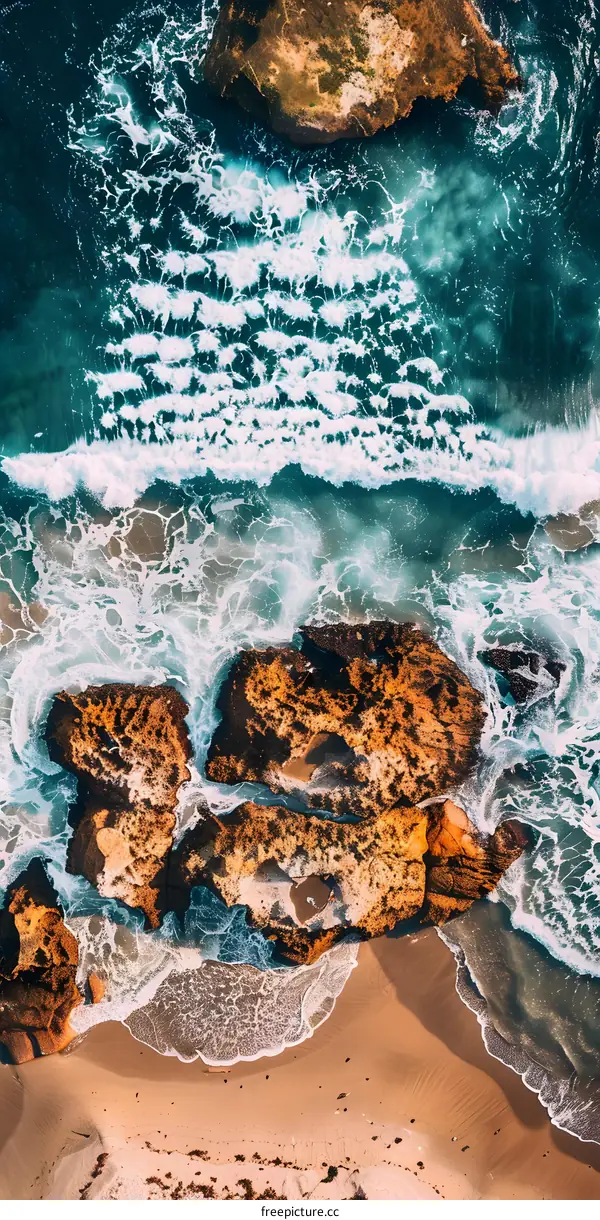 Aerial View of Ocean Waves Crashing on Rocks and Beach