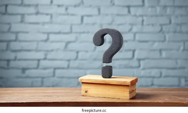 Question Mark on Wooden Pedestal Against Brick Wall