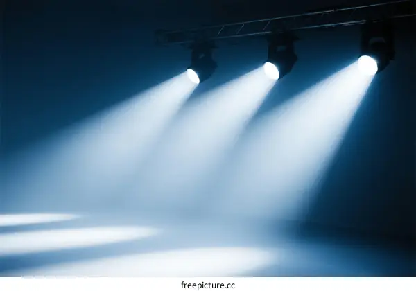 Three bright stage spotlights emitting beams in blue tones