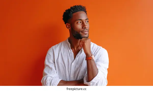 Thoughtful Black Man in a Light Shirt Against Orange Background