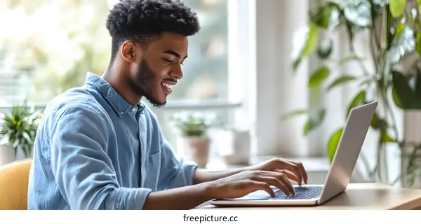 Smiling Black Man Using Laptop Computer In Modern Office
