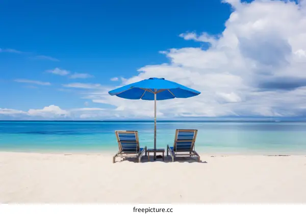 Two Beach Chairs and Umbrella on White Sand Beach Under Blue Sky and Sea