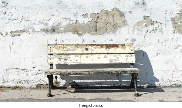 Old Wooden Park Bench Against a White Wall