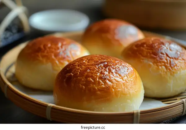 Four golden brown buns on a bamboo steamer