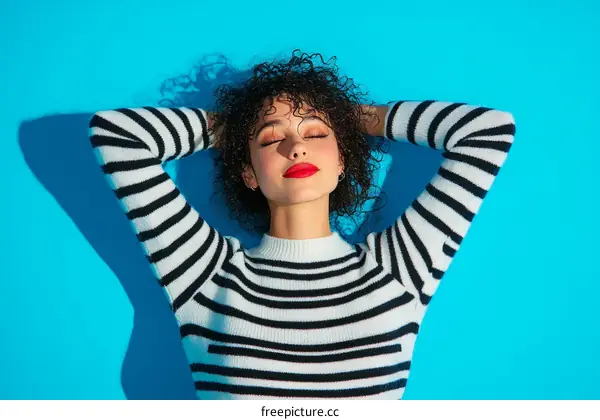 Relaxing Woman in Striped Sweater against Blue Background