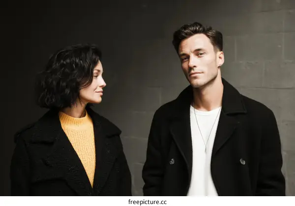Stylish Couple Posing Against a Grey Wall