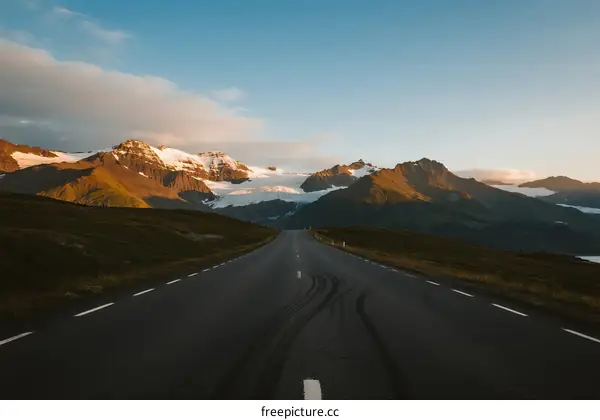 Scenic road leading through mountainous area with snow-capped peaks