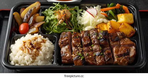 A delicious and healthy Japanese bento box with steak, rice, vegetables and salad