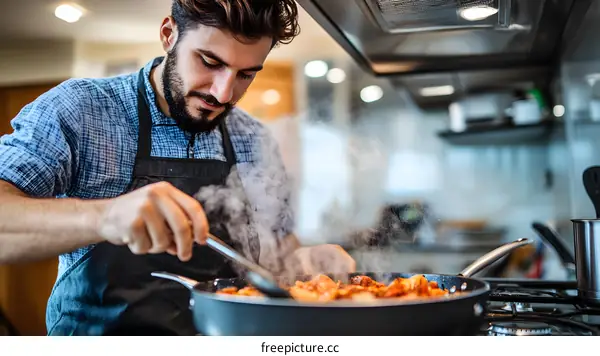 Man Cooking in Kitchen with Steam from Frying Pan
