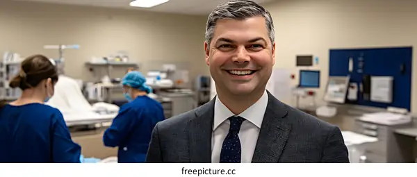 Smiling Man in a Suit Standing in a Hospital Room