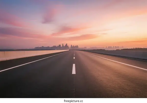 Sunset view of an empty highway leading to a city skyline