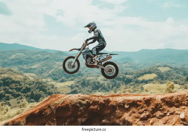Motocross dirt bike rider jumping over a hill