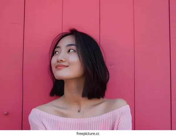 Young Asian Woman Smiling Looking Up at Pink Wall