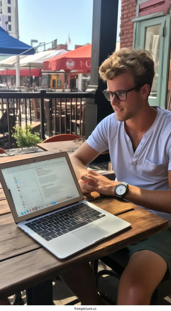 Young male professional working on his laptop outdoors at a cafe