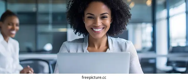Smiling Black Woman Using Laptop In Office