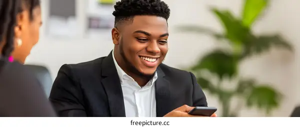 Smiling African American Man Looking at His Phone in an Office