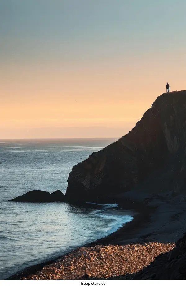 Man standing alone on a cliff overlooking the ocean