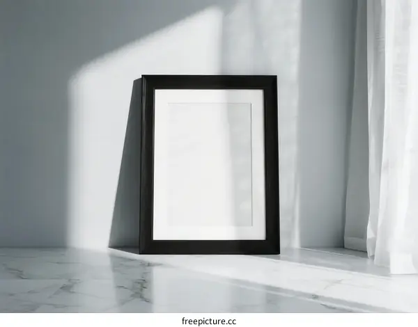 Black frame with white empty space placed on marble floor near window