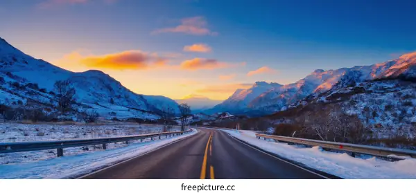 Winter Road Through Snowy Mountains at Sunrise