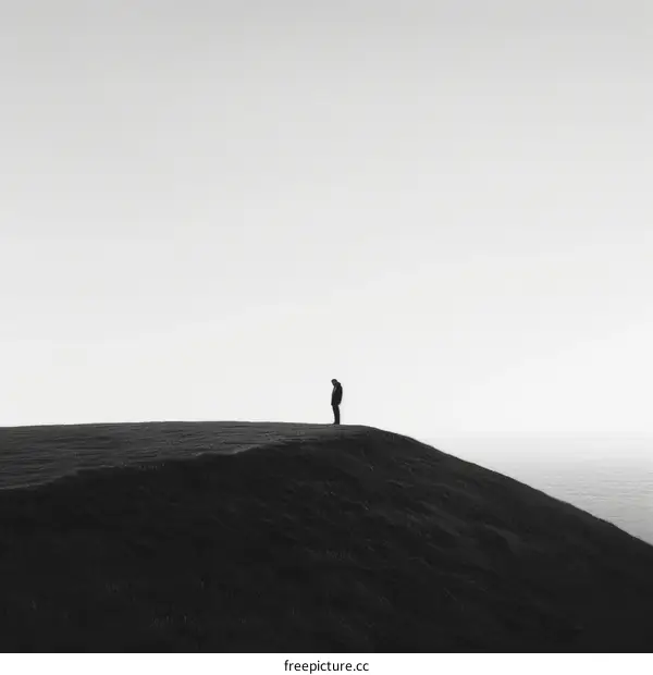 Man standing alone on a hilltop overlooking the sea