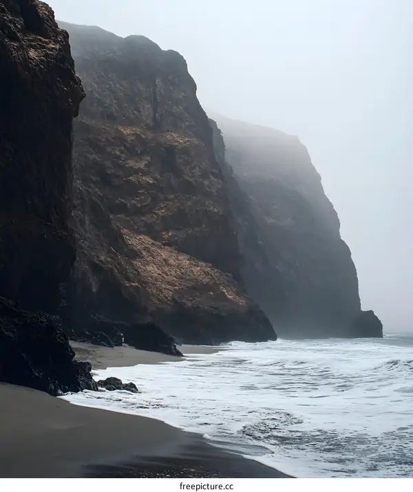 Misty Beach Coastline With Rocky Cliffs