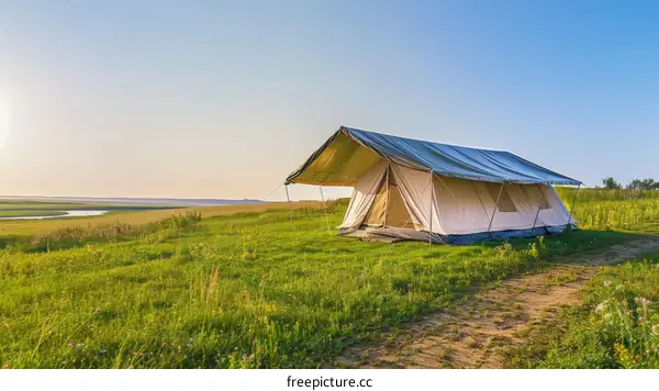 Large tent on the green field near the river at sunset
